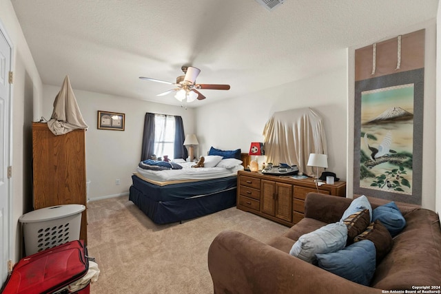 bedroom with a textured ceiling, light colored carpet, and ceiling fan