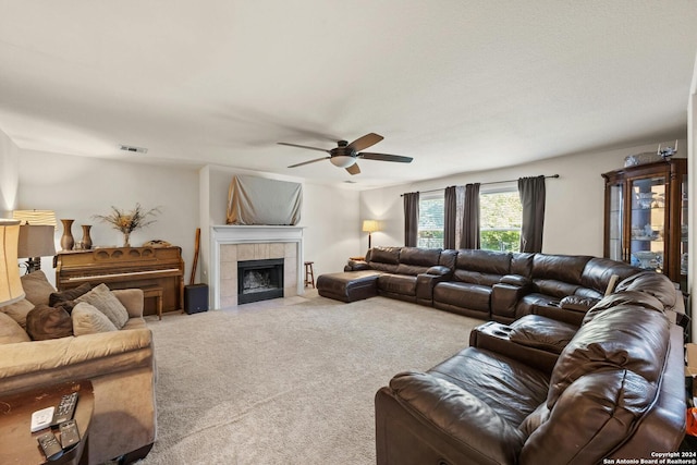 living room featuring a tile fireplace, carpet floors, and ceiling fan