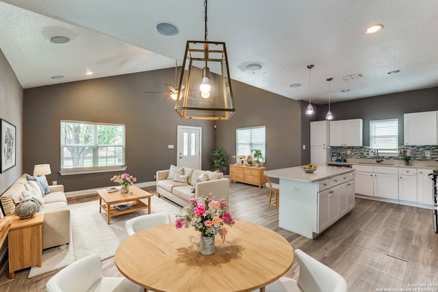 kitchen featuring tasteful backsplash, a kitchen island, sink, hanging light fixtures, and white cabinets