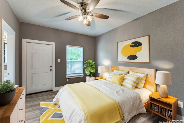 bedroom with a textured ceiling, ceiling fan, and hardwood / wood-style flooring