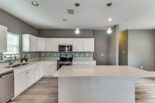 kitchen featuring decorative light fixtures, white cabinetry, a center island, and stainless steel appliances