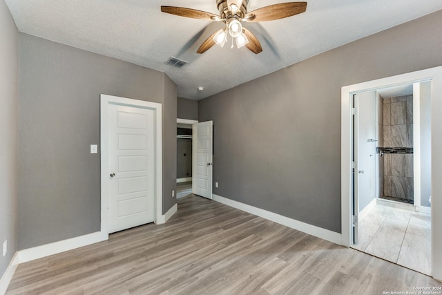 unfurnished bedroom featuring ceiling fan, light wood-type flooring, and a textured ceiling