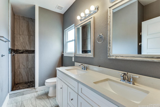 bathroom with toilet, tiled shower, and vanity