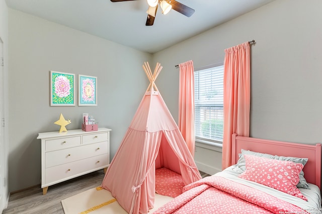 bedroom with ceiling fan, multiple windows, and hardwood / wood-style flooring