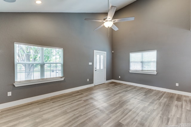 unfurnished living room featuring ceiling fan, light wood-type flooring, and high vaulted ceiling