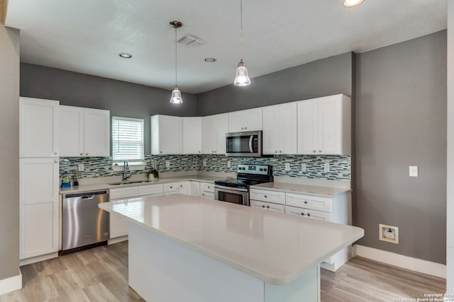 kitchen with light wood-type flooring, a center island, sink, white cabinetry, and stainless steel appliances