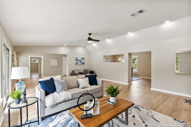 living room featuring ceiling fan, lofted ceiling, and light wood-type flooring