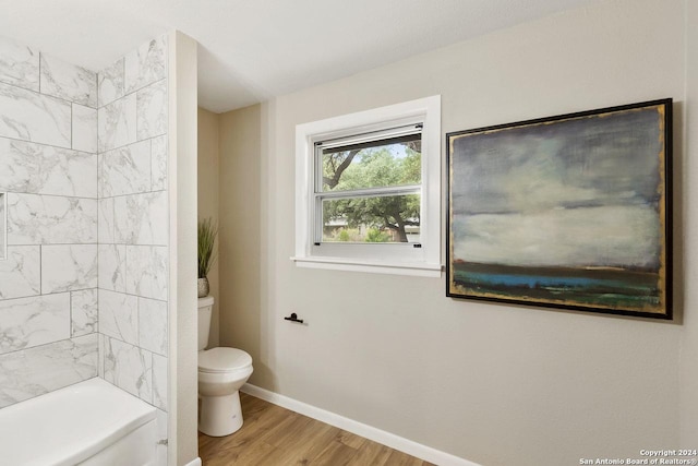 bathroom featuring tiled shower / bath combo, hardwood / wood-style flooring, and toilet