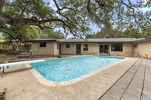 view of swimming pool featuring a diving board and a patio