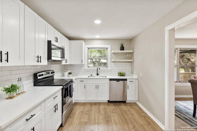 kitchen with decorative backsplash, appliances with stainless steel finishes, light wood-type flooring, sink, and white cabinets