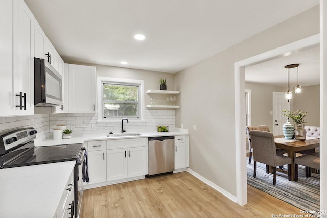 kitchen featuring decorative backsplash, appliances with stainless steel finishes, light wood-type flooring, sink, and white cabinetry