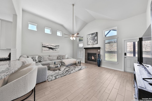 living room featuring a tile fireplace, vaulted ceiling, and ceiling fan