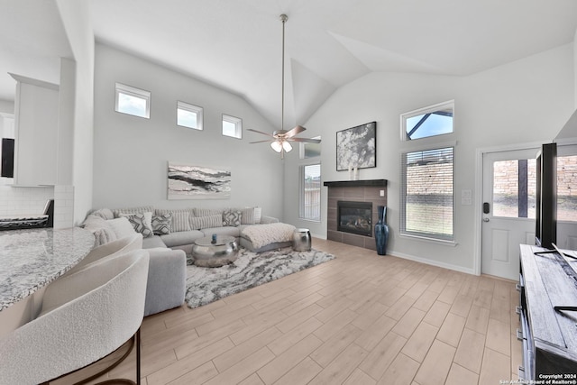 living room with a tile fireplace, vaulted ceiling, and ceiling fan