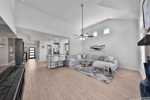 living room featuring ceiling fan, a high ceiling, and a tiled fireplace