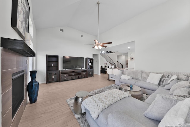 living room with ceiling fan, high vaulted ceiling, and light hardwood / wood-style flooring