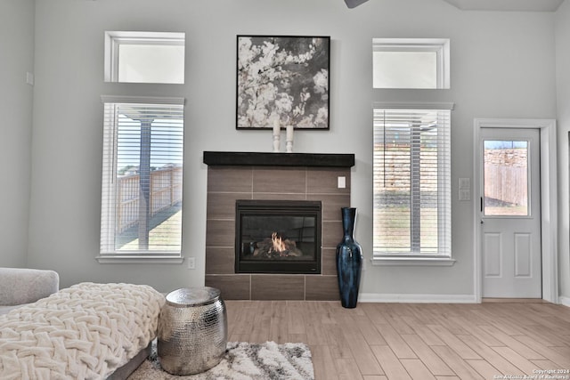 living room with a tiled fireplace, a wealth of natural light, and hardwood / wood-style flooring