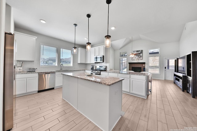 kitchen with white cabinetry, hanging light fixtures, a kitchen island, and stainless steel appliances