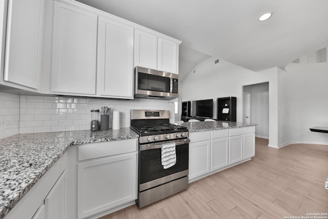 kitchen with light stone countertops, white cabinets, light wood-type flooring, and appliances with stainless steel finishes