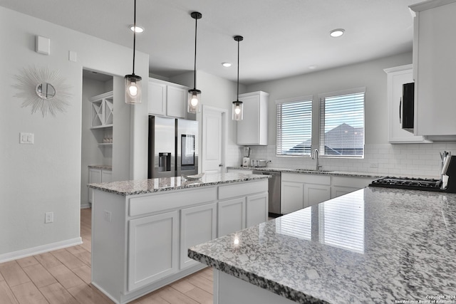 kitchen featuring a center island, white cabinetry, hanging light fixtures, and appliances with stainless steel finishes