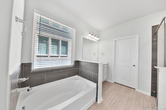 bathroom with hardwood / wood-style flooring, vanity, and a bathtub