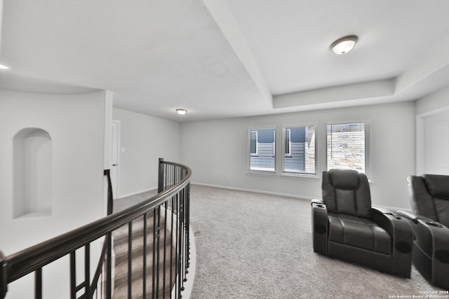 sitting room featuring a raised ceiling and carpet floors