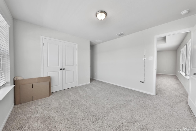 unfurnished bedroom with light colored carpet and a closet