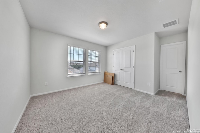 unfurnished bedroom with light carpet and a closet