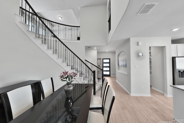 dining space featuring light hardwood / wood-style floors and a towering ceiling