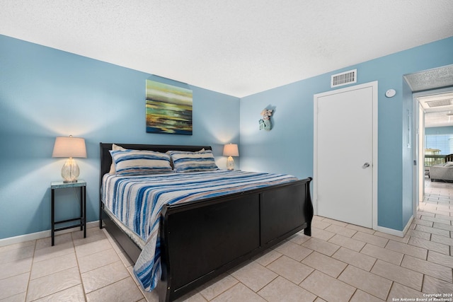 bedroom with a textured ceiling and light tile patterned flooring