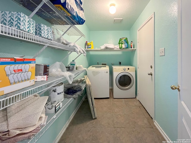 washroom featuring a textured ceiling, independent washer and dryer, and tile patterned floors