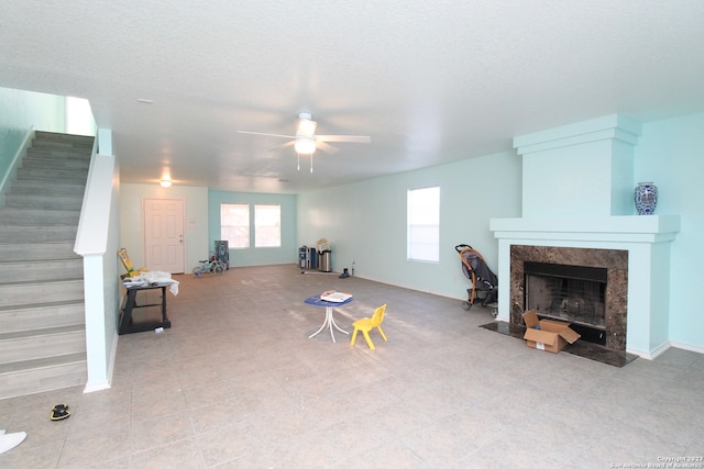 living room with light tile patterned flooring, a fireplace, a textured ceiling, and ceiling fan