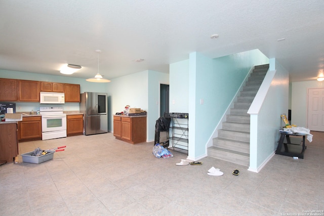 kitchen with hanging light fixtures, white appliances, and light tile patterned floors