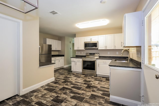 kitchen with white cabinets, appliances with stainless steel finishes, and sink