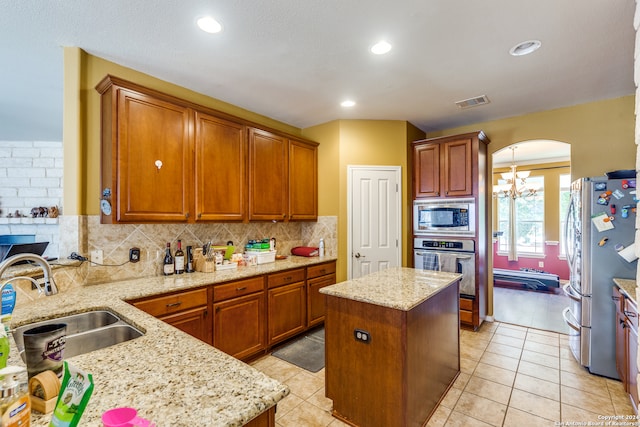 kitchen featuring light tile patterned floors, a center island, backsplash, appliances with stainless steel finishes, and sink