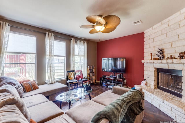 living room featuring a stone fireplace, dark hardwood / wood-style floors, and ceiling fan