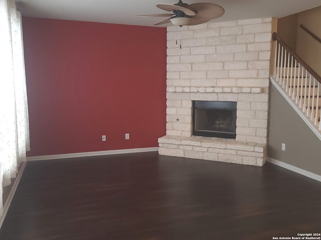 unfurnished living room with brick wall, a brick fireplace, hardwood / wood-style flooring, and ceiling fan