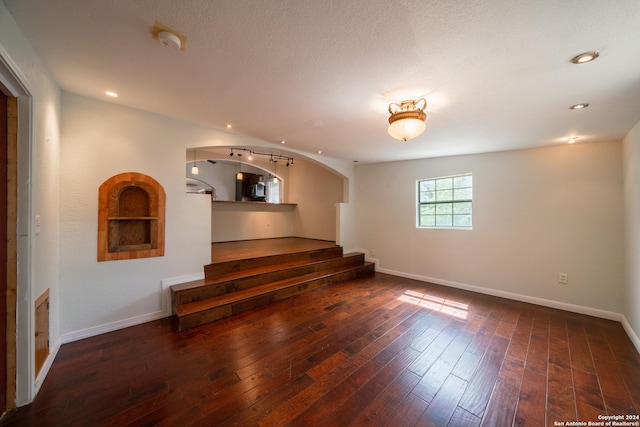 empty room with a textured ceiling and dark hardwood / wood-style floors