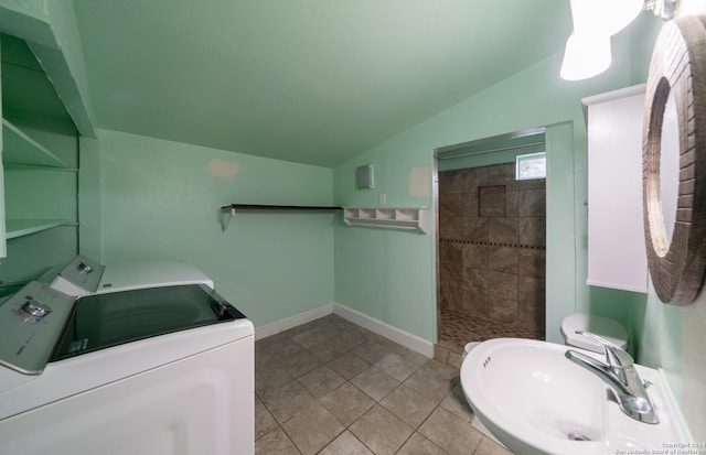 bathroom with walk in shower, vaulted ceiling, tile patterned floors, washing machine and dryer, and sink