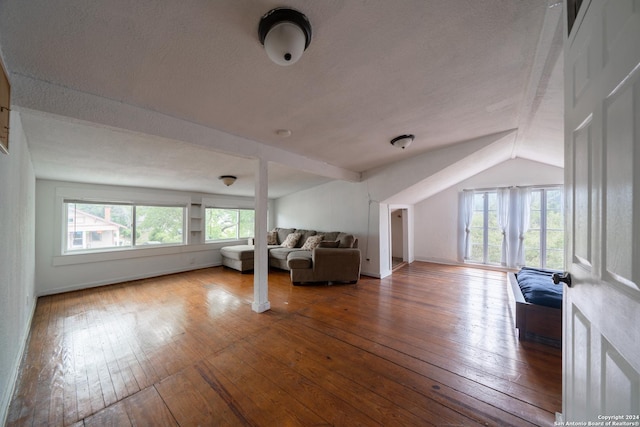 unfurnished living room featuring lofted ceiling, wood-type flooring, and a textured ceiling