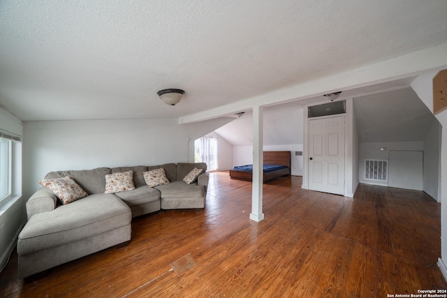 living room with a textured ceiling, vaulted ceiling, and hardwood / wood-style floors