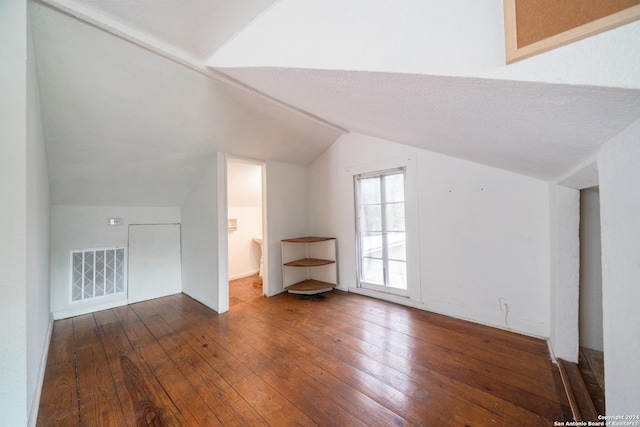 additional living space with vaulted ceiling, dark hardwood / wood-style floors, and a textured ceiling