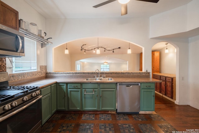 kitchen with kitchen peninsula, appliances with stainless steel finishes, a healthy amount of sunlight, hanging light fixtures, and sink