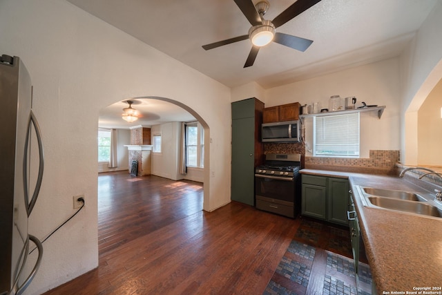 kitchen featuring ceiling fan, appliances with stainless steel finishes, decorative backsplash, dark hardwood / wood-style flooring, and sink