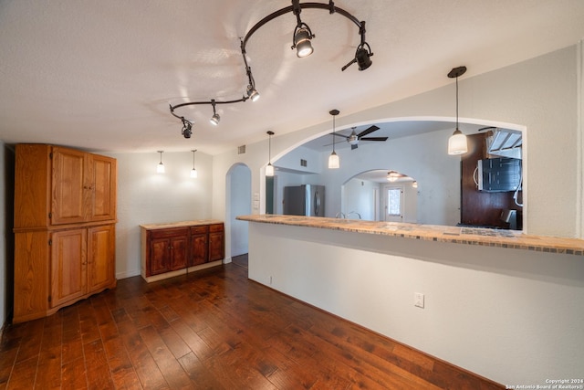 kitchen with kitchen peninsula, ceiling fan, stainless steel appliances, dark wood-type flooring, and pendant lighting