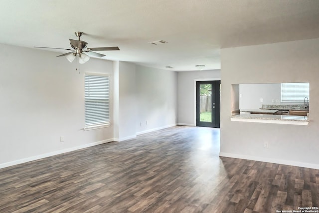 unfurnished living room featuring dark wood-type flooring and ceiling fan