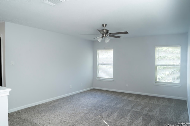 carpeted spare room featuring plenty of natural light and ceiling fan