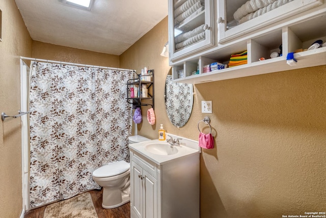 bathroom with vanity, hardwood / wood-style flooring, toilet, a textured ceiling, and walk in shower