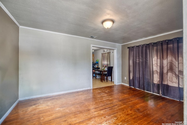 spare room featuring a textured ceiling, wood-type flooring, and ornamental molding