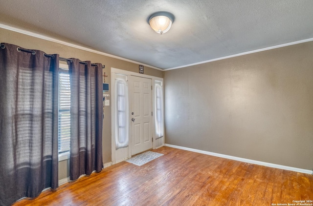 foyer entrance with wood-type flooring, a textured ceiling, and ornamental molding