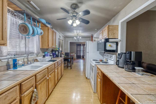 kitchen featuring tile countertops, white appliances, sink, ceiling fan, and light hardwood / wood-style floors